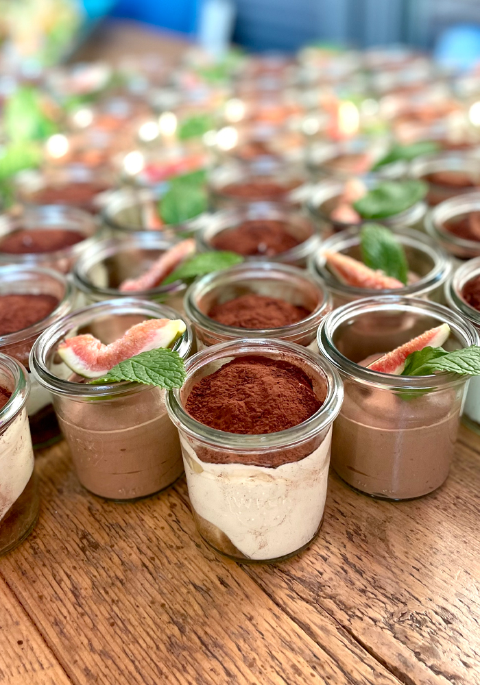 Eine Vielzahl von Schokoladenmousse-Desserts, liebevoll in kleinen Gläsern präsentiert, jedes garniert mit einer frischen Minze und einer Grapefruitscheibe.