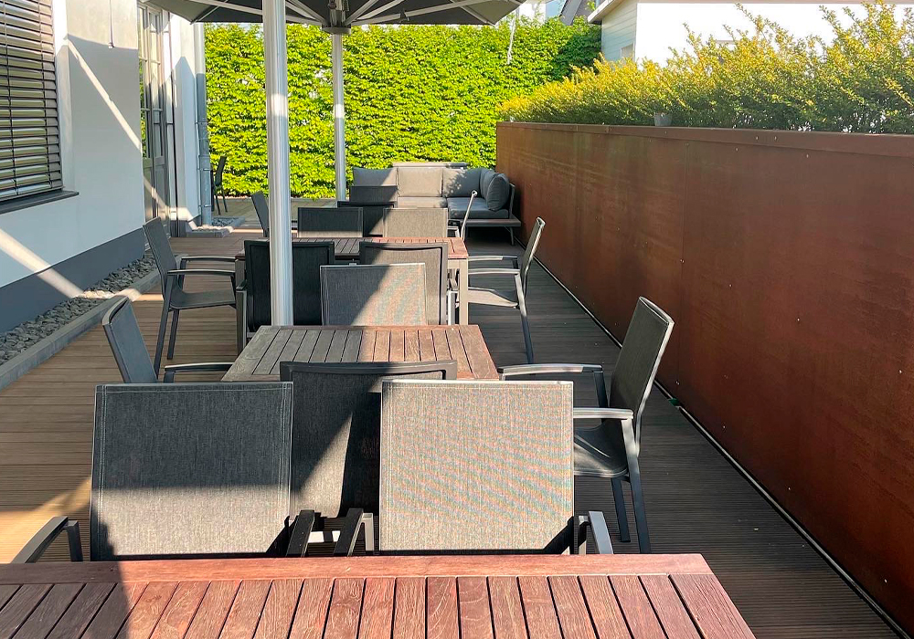 Eine sonnige Terrasse im Denkwerk Herford mit elegant gedeckten Tischen und einer gemütlichen Lounge-Ecke, bereit für ein Outdoor-Event.