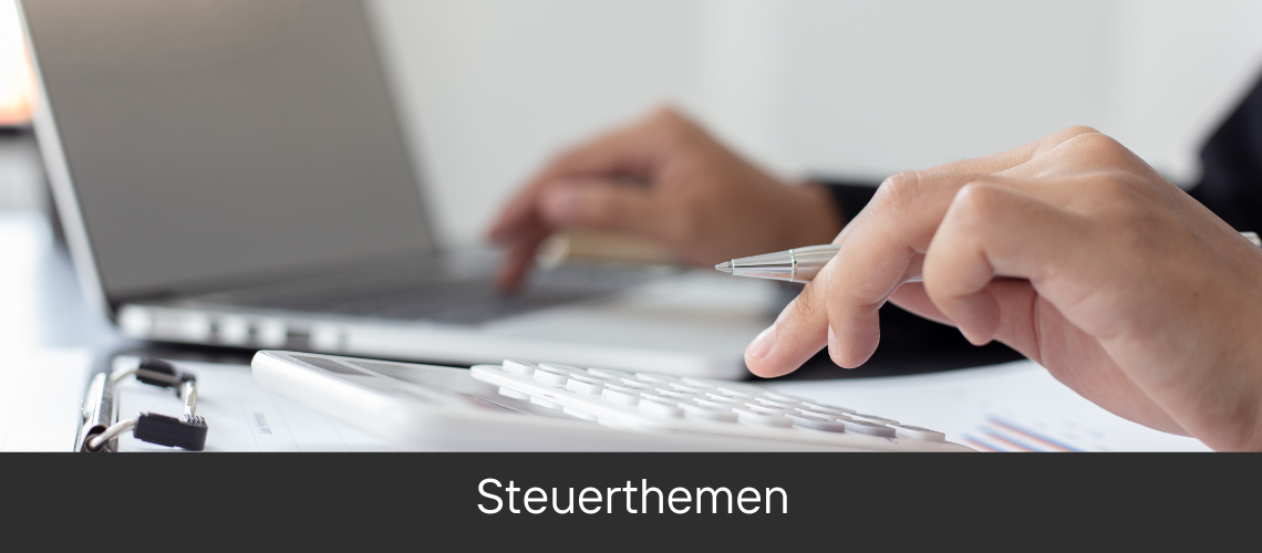 Eine Person tippt auf einem Laptop und hält einen Stift, neben liegen Dokumente und ein Taschenrechner, was auf die Bearbeitung von Steuerthemen hindeuten könnte.