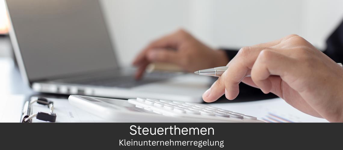 Person arbeitet an einem Laptop und hält einen Stift über eine Tastatur, im Vordergrund sind ein Taschenrechner und Dokumente zu sehen, mit dem Text 'Steuerthemen: Kleinunternehmerregelung' auf dem Bildschirm.