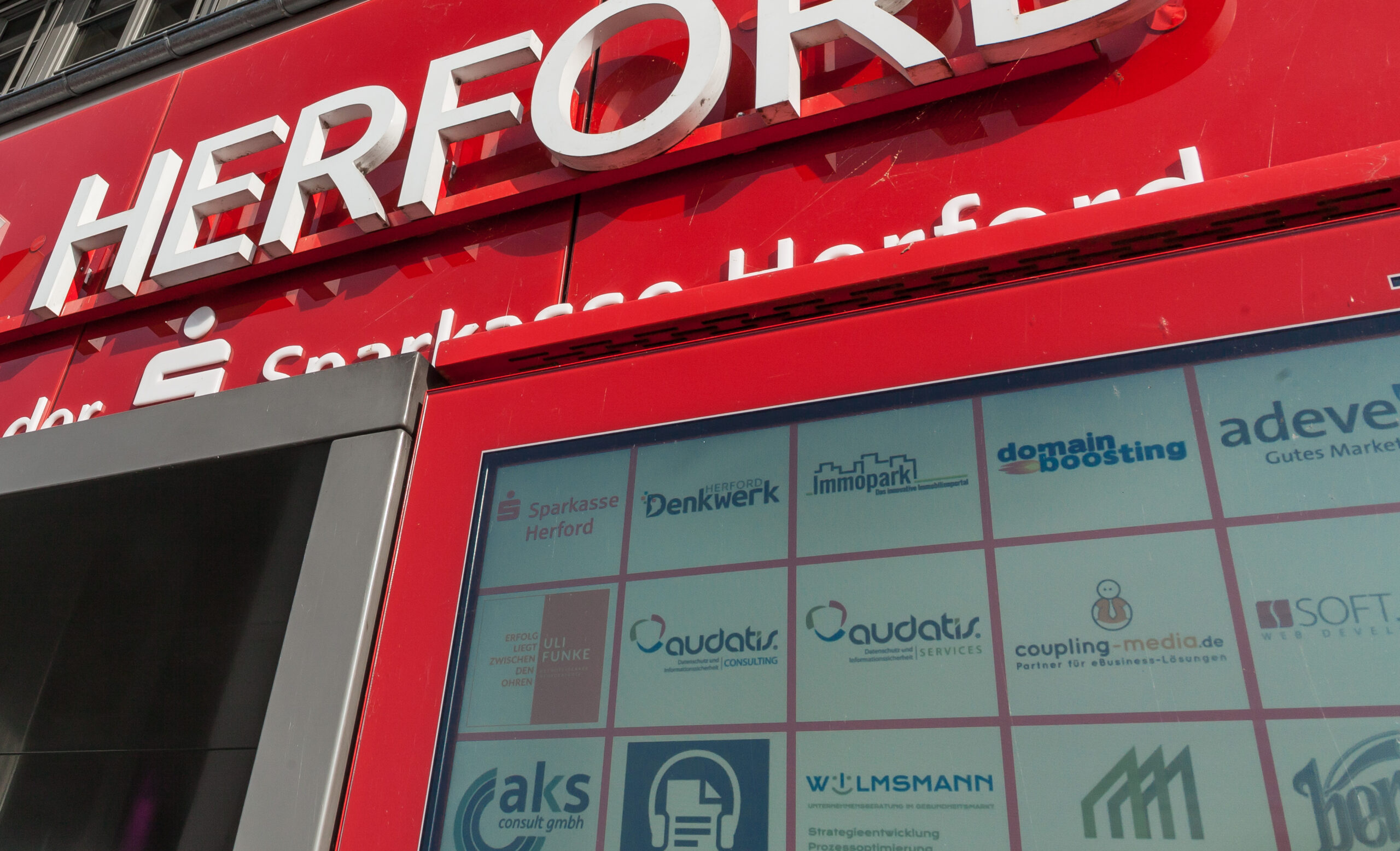 Denkwerk Herford mit digitaler Werbeanzeige, die verschiedene Unternehmenslogos und Dienstleistungen präsentiert.