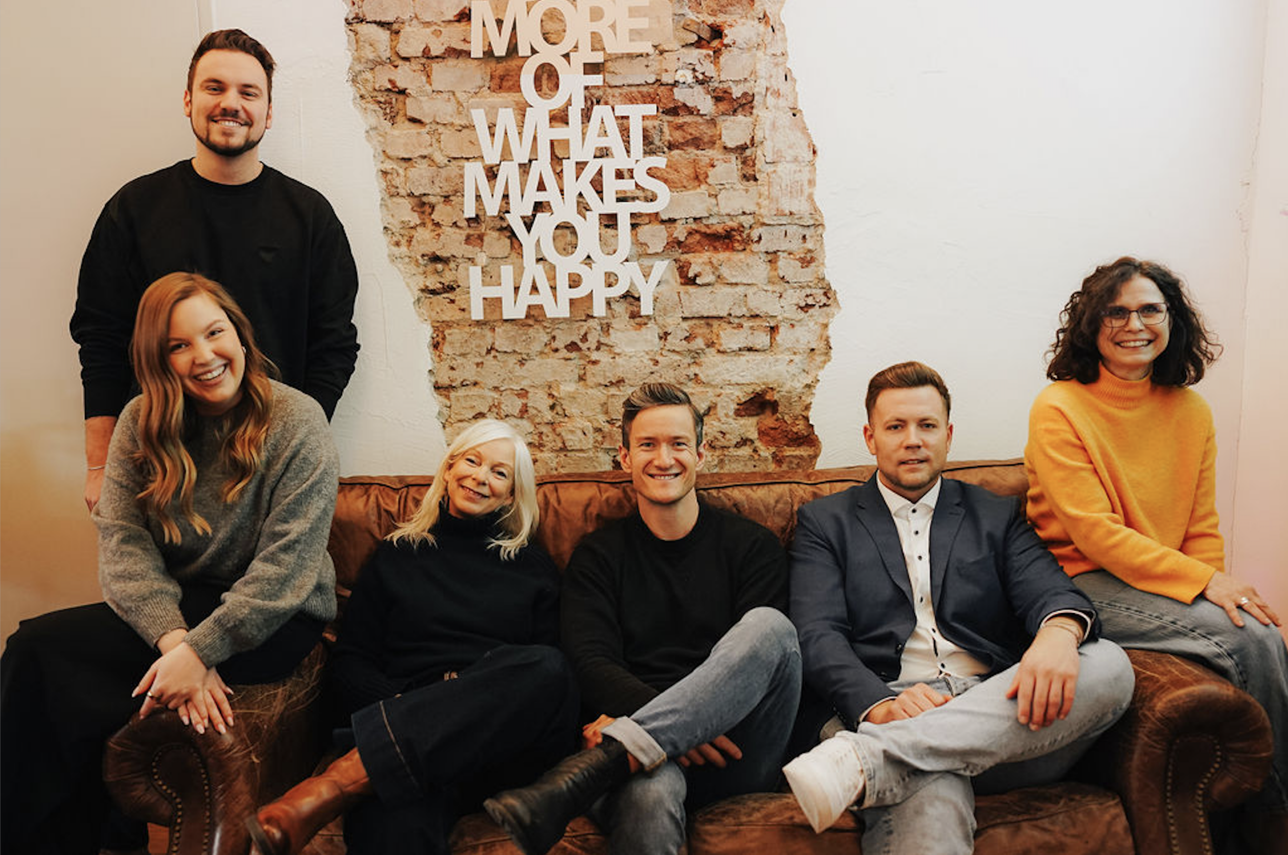 Mehrere Personen stehen und sitzen im Denkwerk Herford im Austausch miteinander; eingeblendet ist der Titel des Gründungsformats: Gründungstreff.