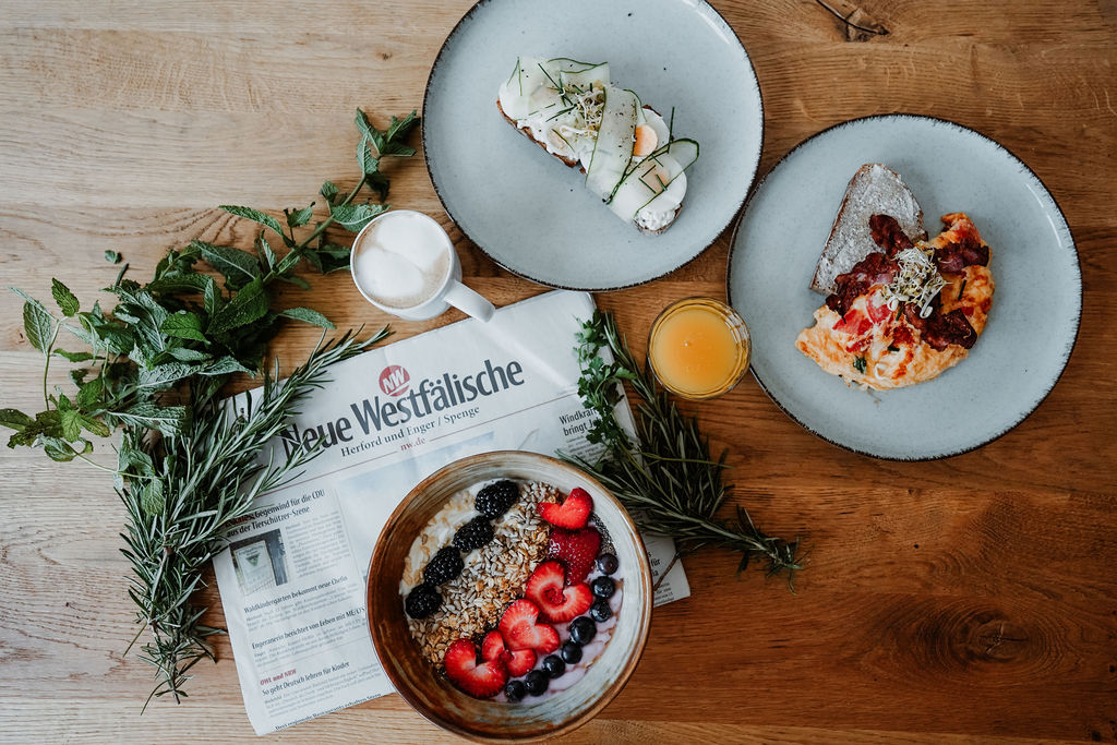 Vielfältiges Frühstück mit Frühstücksbowl, Rührei, belegtem Brot, Kaffee und Orangensaft im Denkwerk Herford.