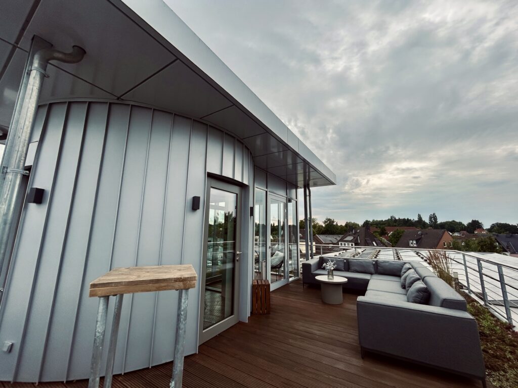Moderne Dachterrasse des Denkwerks Herford mit gemütlicher Lounge, Holzdeck und weitem Blick über die Dächer der Stadt – ideal für Pausen, Networking und Outdoor-Events.