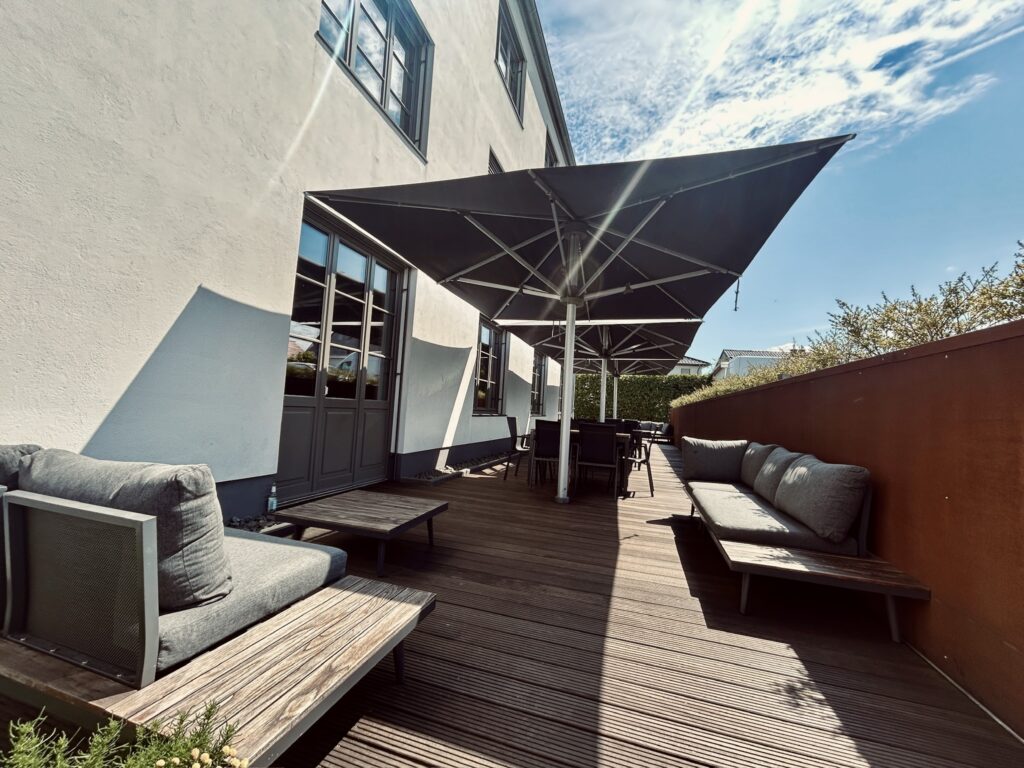 Großzügige Außenterrasse des Denkwerks Herford mit Loungemöbeln, Sitzgruppen und Sonnenschirmen – ideal für Networking, Meetings und entspannte Pausen im Freien.