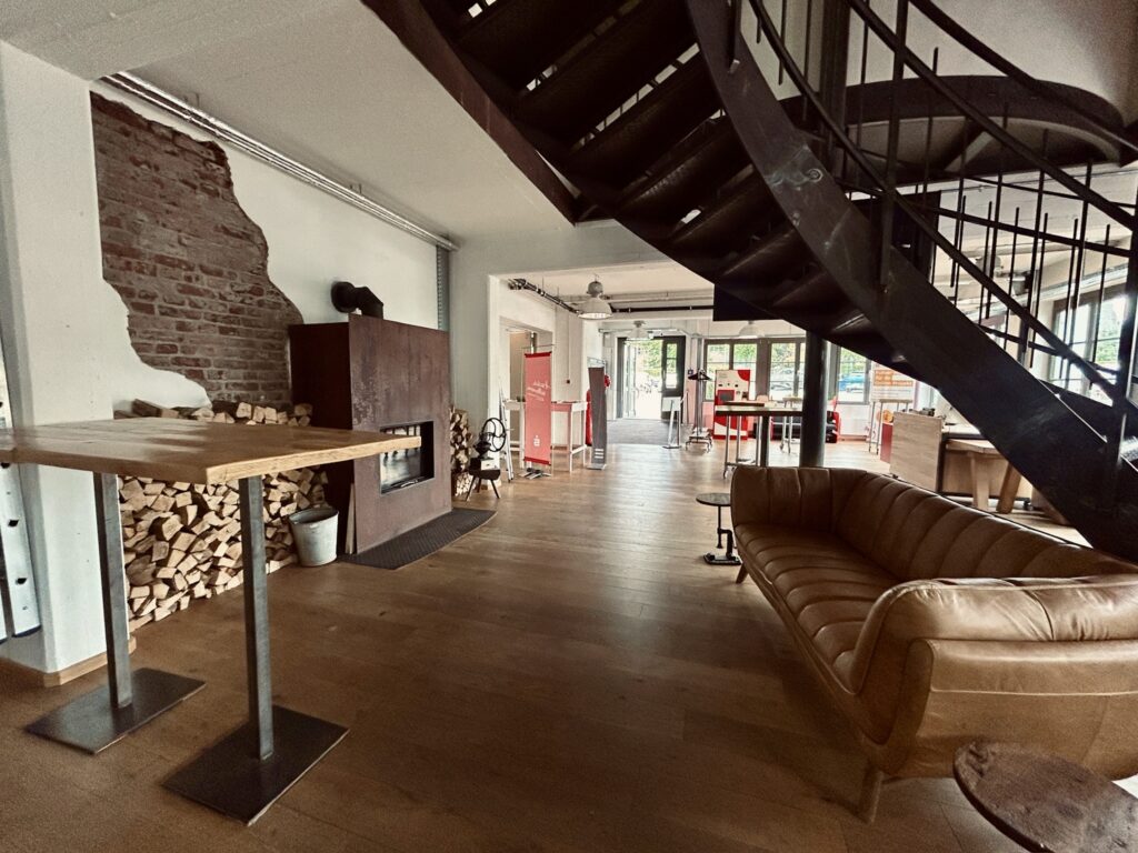 Moderne Lobby im Denkwerk Herford mit Kamin, Lounge-Sitzbereich, Industriearchitektur und offener Atmosphäre für Empfang, Networking und Veranstaltungen.